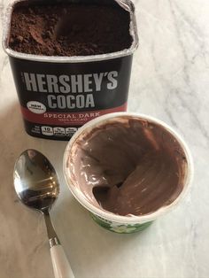 a cup of chocolate ice cream next to a scoop of hershey's cocoa