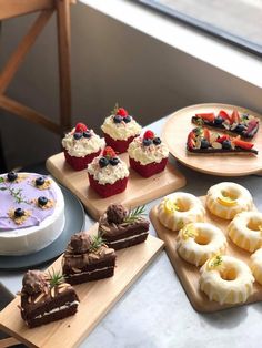 several desserts are arranged on wooden trays near each other, including cakes and cupcakes