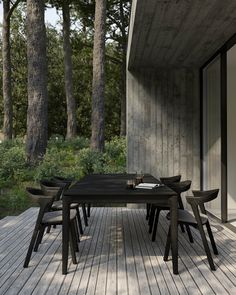 a table and chairs on a wooden deck with trees in the backgrounge