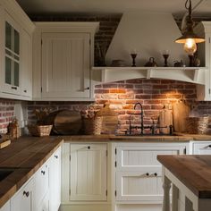 a kitchen with white cabinets and wooden counter tops next to a brick wall in the background