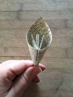 a person is holding a rolled up piece of paper that looks like an origami flower