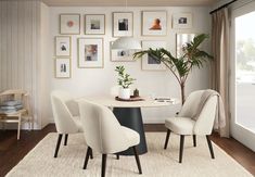 a dining room table with four chairs and a potted plant in the center, surrounded by pictures on the wall