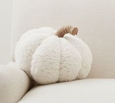 a white pumpkin shaped pillow sitting on top of a couch next to an armrest