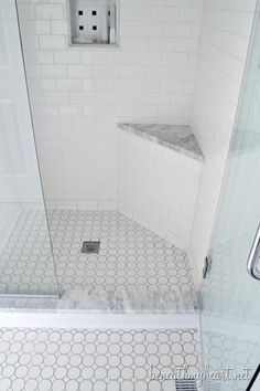 a white tiled bathroom with a shower stall