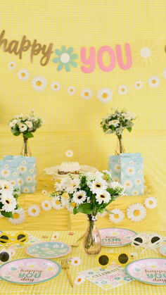 the table is set up for a birthday party with sunflowers and daisies