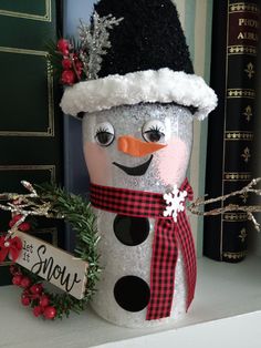 a snowman with a hat and scarf is sitting on a shelf next to some books