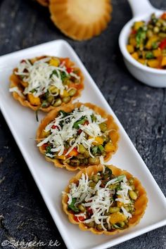 three small appetizers on a white plate with cheese and vegetables in the middle