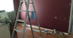 a ladder is in the middle of a room with red walls and wood flooring