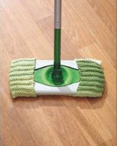 a green mop on the floor with a handle