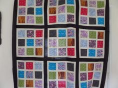 a quilted wall hanging on the side of a door with different colored squares in it