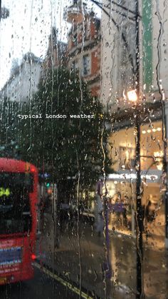 a red double decker bus driving down a rain soaked street