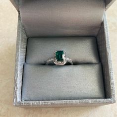 an engagement ring in a box with a green stone on the top and bottom part