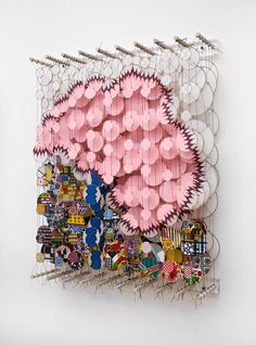 an art piece made out of many different objects on a white wall with pink and blue accents