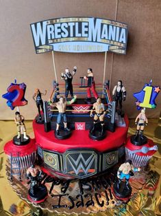 a cake with wrestling figurines sitting on it's sides and the words wrestle mania above them