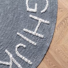 an area rug with the word hello written on it in white and grey colors, sitting on a wooden floor