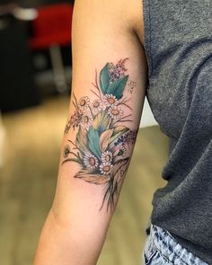 a woman's arm with flowers and leaves tattooed on the left side of her arm