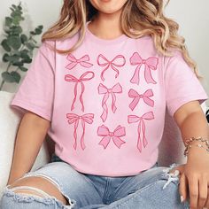 Introducing our Coquette Bow Graphic Tee – a charming addition to your casual wardrobe. This pink-colored, short-sleeve tee features a delicate bow graphic, adding a touch of elegance and femininity to your everyday style. *Will Ship in 3-5 Days* Size Suggestions: Small: 2-4 Medium: 6-8 Large: 10-12 XL: 14-16 2XL: 18-20 3XL: 22-24 Fabric Content: 52% Cotton 48% Polyester Care Instructions: Machine wash, cold. Tumble dry, low. Do not iron decoration. SKU: #242587 Trendy Crew Neck T-shirt With Bow, Trendy Summer T-shirt With Bow, Casual Summer T-shirt With Pink Bow, Feminine Cotton Short Sleeve T-shirt, Casual Short Sleeve T-shirt With Pink Bow, Casual Crew Neck T-shirt With Bow Print, Cute Pink T-shirt With Bow, Cute Pink Short Sleeve T-shirt, Summer Bow Print Short Sleeve Tops