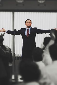 a man standing in front of a crowd holding his arms out with both hands up