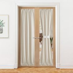 an open door with white curtains and wood floors in front of a painting on the wall