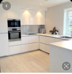 an empty kitchen with white cabinets and wood flooring is pictured in this image from the front view