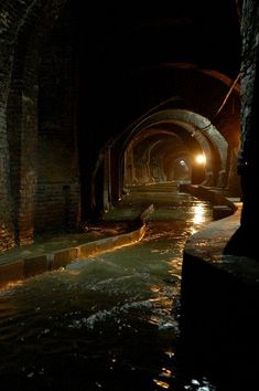 an underground tunnel with water running through it and lights shining in the dark on either side