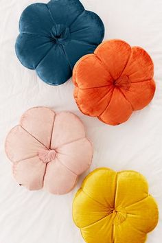 four different colored cushions on a white surface