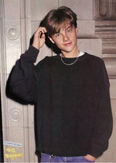 a young man is talking on his cell phone while standing in front of a door