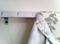 a curtain is hanging on the wall next to a towel rack with an object in it