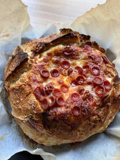 a pepperoni pizza sitting on top of a piece of wax paper