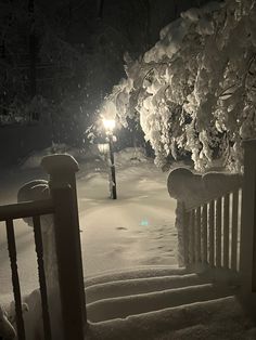 a snow covered park bench next to a street light