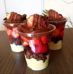 three dessert cups with strawberries, chocolate and cream in them sitting on a table