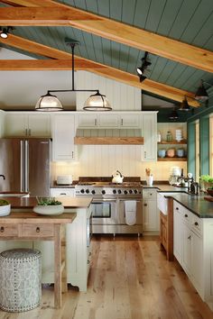 an open kitchen with white cabinets and wood flooring is pictured in this image, there are two pendant lights above the island