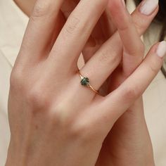 a close up of a person wearing a ring with a green gemstone on it