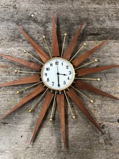 a clock that is on the side of a wooden wall and has gold accents around it