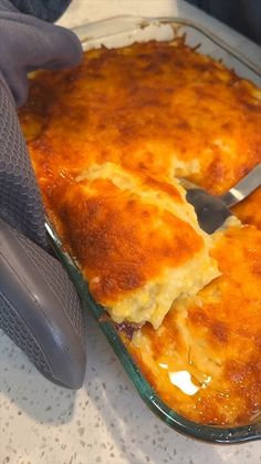 a person cutting into a casserole dish with a knife