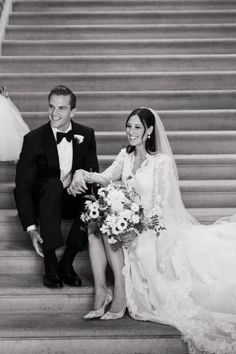 a bride and groom sitting on the steps at their wedding ceremony in black and white