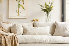 a living room with white couches and flowers in vases on the side table