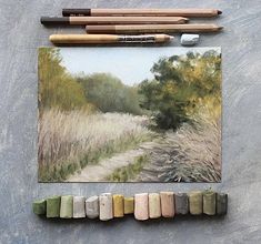 some pastel crayons are sitting on a table next to an art piece