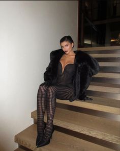 a woman is sitting on some stairs wearing black stockings and high heeled boots with a fur coat over her shoulders