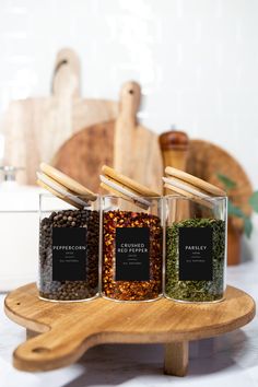 three jars filled with spices sitting on top of a wooden tray