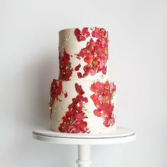 a three tiered cake with red flowers on it sitting on top of a white plate