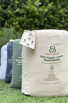 three bags of organic cotton sit on the grass in front of some bushes and trees