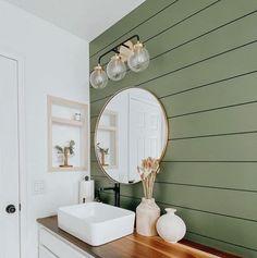 a white sink sitting on top of a wooden counter next to a mirror and vase