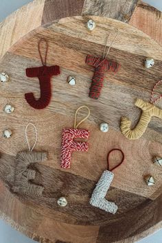 several ornaments are hanging on a wooden board with string and bead work in the shape of letters