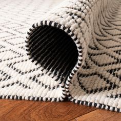 a white rug with black and white designs on the bottom is laying on a wooden floor