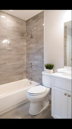 a white toilet sitting in a bathroom next to a bath tub and shower head mounted on a wall