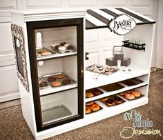 a bakery display case with cupcakes and pastries in the front, including donuts