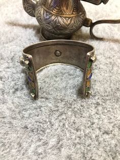 Beautiful antique silver berber bracelet from the Anti Atlas region in Morocco, around 1950. The decoration is very refined, there's some remains of niello deco and enamel in yellow ,blue and green. This Bracelet show an exquisite quality of engraved work with flower motifs. The center stone is an antique glass in red color. High quality of silver, very smooth and nice patina. Min Width : 3,2cm Max Width : 4,7cm Inner diameter : 6cm Weight : 77,3cm Traditional Inlay Cuff Bangle Bracelet, African Bracelets, Moroccan Jewelry, Flower Motifs, Silver Heart Ring, Enamel Bracelet, Antique Glass, Silver Coins, Blue And Green