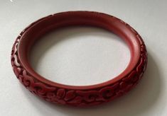 This vintage Chinese carved red cinnabar bangle is a stunning piece of jewelry that is sure to make a statement. The bangle features intricate carvings of traditional Chinese motifs, such as dragons, flowers, and geometric patterns, all done in a vibrant red hue. Cinnabar is a mineral that has been used in Chinese art and jewelry for centuries, prized for its rich color and durability. This bangle would make a beautiful addition to any jewelry collection and is sure to be a conversation starter. Intaglio Bangle Bracelets As A Gift, Intaglio Bangle Bracelet As Gift, Carved Bangle Bracelet For Gift, Carved Bangle Bracelet As A Gift, Red Vintage Bangle For Wedding, Traditional Carved Round Bangle, Traditional Carved Bangle, Traditional Round Carved Bangle, Traditional Carved Bangle Gift