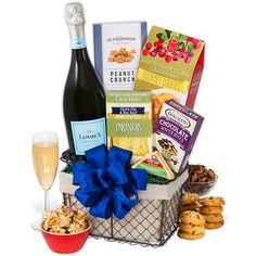 a basket filled with wine, cookies and snacks next to a glass of champagne on a table